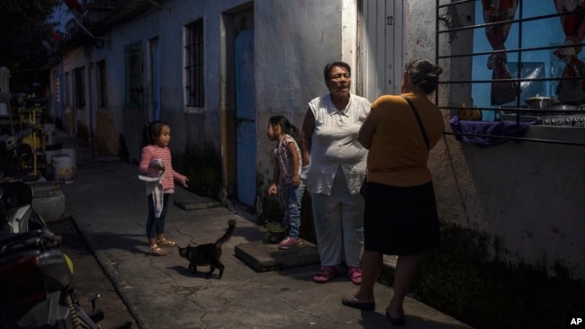 Eglisa Arias, center, talks outside the home she is renting in Frontera in the state of Tabasco, Mexico, Nov. 29, 2023. Arias was driven from her home when a fast-moving sea-level rise destroyed her coastal community of El Bosque.