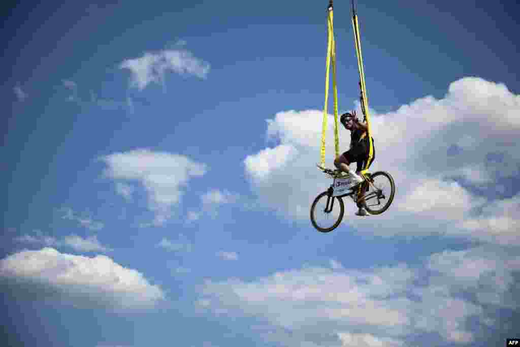 A spectator sits atop a bicycle suspended above the race route during the 16th stage of the 111th edition of the Tour de France cycling race, 188,6 km between Gruissan and Nimes, southern France.