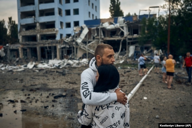 FILE - A couple reacts after the Russian shelling in Mykolaiv, Ukraine, Wednesday, Aug. 3, 2022. According local media, supermarket, high-rise buildings and pharmacy were damaged. (AP Photo/Kostiantyn Liberov)