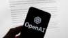 FILE - The OpenAI logo is seen on a mobile phone in front of a computer screen displaying output from ChatGPT, March 21, 2023, in Boston. 