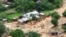 FILE - People walk by houses damaged by Tropical Cyclone Freddy, around 100 km outside Blantyre, Malawi, March 18, 2023. 