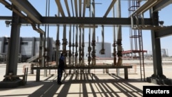 (FILE) A worker examines and adjustes a valve in the facilities of Kurdish oil company KAR, in Erbil, Iraq, July 21, 2022.