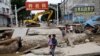 Seorang pria menggendong seorang anak berjalan melintasi jembatan yang rusak setelah hujan dan banjir akibat sisa-sisa Topan Doksuri, di Zhuozhou, Provinsi Hebei, China, 7 Agustus 2023. (REUTERS/Tingshu Wang)