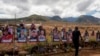 FILE - A visitor walks by photos of victims of the August 2023 wildfire at a memorial near the Lahaina Bypass highway on July 6, 2024, in Lahaina, Hawaii. 