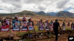 FILE - A visitor walks by photos of victims of the August 2023 wildfire at a memorial near the Lahaina Bypass highway on July 6, 2024, in Lahaina, Hawaii. 