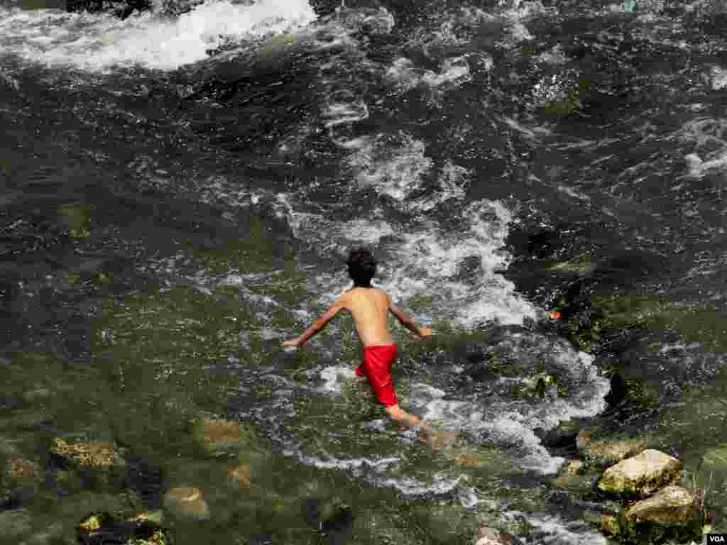 A young boy finds relief in the River Nile amid the intense heat. Climate projections by the International Energy Agency show this populous and water-scarce desert country is warming faster than the global average. North of Cairo, Egypt, May 6, 2024. (Hamada Elrasam/VOA)