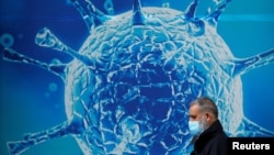 一名男子走过英国一家研究生物病毒的科研中心外的广告墙。（2020年8月3日）