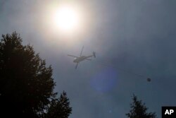 A helicopter carries water over the Park Fire near Forest Ranch, California, July 30, 2024.