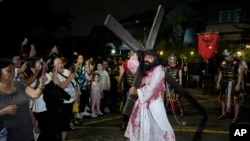 FILE - Penduduk desa memotret seorang pria yang berperan sebagai Yesus Kristus dalam pertunjukan "Senakulo" dalam rangka memperingati Pekan Suci Pra Paskah di kota Quezon, Filipina, Rabu, 27 Maret 2024. (AP/Aaron Favila)