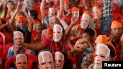 Pendukung Perdana Menteri India Narendra Modi mengenakan topeng bergambar Modi yang menutupi wajahnya, saat mereka menghadiri kampanye pemilu di Meerut, India, Minggu 31 Maret 2024.