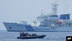 FILE - A Philippine Coast Guard rigid hull inflatable boat passes by the Japanese Coast Guard Akitsushima during a trilateral Coast Guard drill of the U.S., Japan and Philippines near the waters of the disputed South China See in Bataan province, Philippines, June 6, 2023.