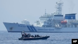  FILE - A Philippine Coast Guard vessel passes by the Japanese Coast Guard Akitsushima during a trilateral Coast Guard drill of the U.S., Japan and Philippines, near the waters of the disputed South China See in Bataan province, Philippines, June 6, 2023. 