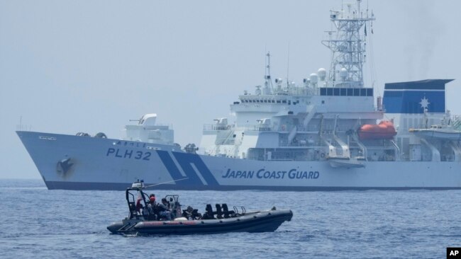  FILE - A Philippine Coast Guard vessel passes by the Japanese Coast Guard Akitsushima during a trilateral Coast Guard drill of the U.S., Japan and Philippines, near the waters of the disputed South China See in Bataan province, Philippines, June 6, 2023. 