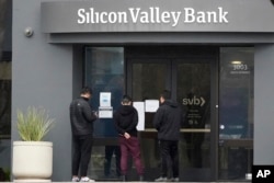 People look at signs posted outside of an entrance to Silicon Valley Bank in Santa Clara, California, March 10, 2023.