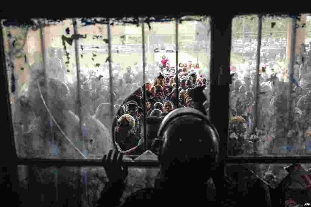 Congolese police officers block a door after voters forced their way into a voting station in Kinshasa, Democratic Republic of Congo.&nbsp;Millions of Congolese head to the polls in a high-stakes general election in which President Felix Tshisekedi is seeking a new term against a fragmented opposition.