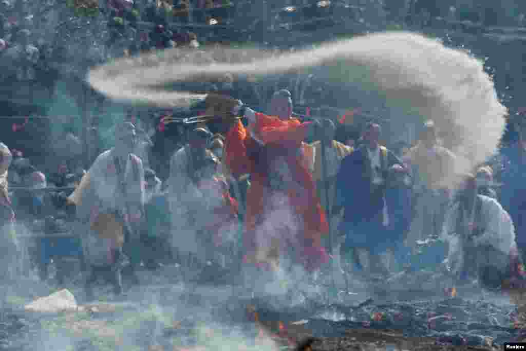 A Buddhist monk throws salt on a large bonfire of wood and Japanese cypress leaves, at the fire-walking festival, called Hiwatari matsuri in Japanese, at Mt.Takao in Tokyo, Japan.