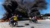 FILE - Motorcyclists drive by burning tires during a police demonstration after a gang attack on a police station that left six officers dead, in Port-au-Prince, Haiti, Jan. 26, 2023.