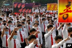 FILE - North Korean youths march toward Kim Il Sung Square during a protest to denounce defectors and South Korean authorities' policy against North Korea, in Pyongyang, June 8, 2020. The signs read, "Give us an order (to punish South Korea)."