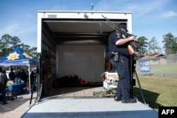 A police officer secures guns to be transported in the back of a truck during a gun buyback program in Houston, Texas, Feb. 18, 2023.