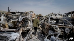 Seorang pria Palestina berjalan di antara mobil-mobil yang hangus di tempat pembuangan sampah, di kota Hawara, dekat kota Nablus, Tepi Barat, Senin, 27 Februari 2023. (AP/Ohad Zwigenberg)