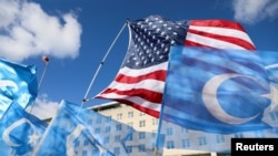 FILE - Flags fly during a rally for Uyghur citizens of China in Washington on Nov. 28, 2022.