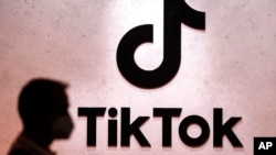 FILE - A visitor passes the TikTok exhibition stands at the Gamescom computer gaming fair in Cologne, Germany, Aug. 25, 2022. 