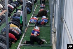 Palestinians pray next to the bodies of those killed after an Israeli military raid on Nur Shams refugee camp in the West Bank, Dec. 27, 2023.