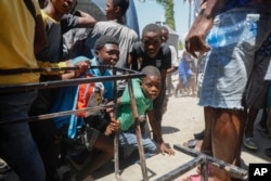 FILE - Youth take cover after hearing gunshots at a public school that serves as a shelter for people displaced by gang violence, in Port-au-Prince, Haiti, March 22, 2024.