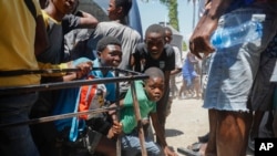 Youth take cover after hearing gunshots at a public school that serves as a shelter for people displaced by gang violence, in Port-au-Prince, Haiti, March 22, 2024.