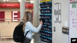 FILE - A student places her cellphone into a phone holder as she enters class at Delta High School, Friday, Feb. 23, 2024, in Delta, Utah. (AP Photo/Rick Bowmer)