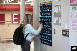 FILE - A student places her cellphone in a phone holder as she enters class at Delta High School, Friday, Feb. 23, 2024, in Delta, Utah. The school requires students to check their phones at the door when entering every class.(AP Photo/Rick Bowmer)