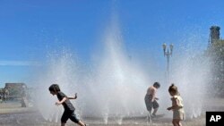 Los niños se divierten mientras se refrescan ante las altas temperaturas bañándose en una fuente en el centro de Portland, Oregón, EEUU, el 12 de mayo de 2023.