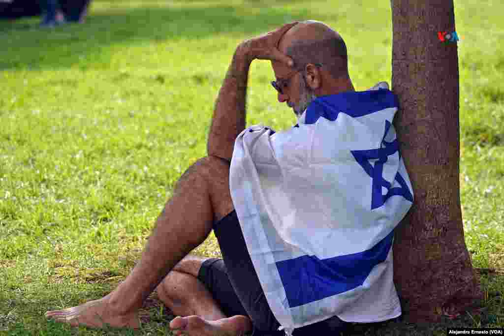 Un hombre permanece cabizbajo, envuelto en una bandera de Israel durante la comida de sabbat organizada hoy en homenaje a las personas que aún permanecen en Gaza secuestradas por el grupo islamita Hamás.