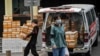 北京一家商业公司的工人正在从一辆小面包车上卸货。（2023年8月8日）