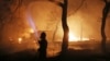 FILE - A firefighter sprays water on the fire in the town of Mati, east of Athens, July 23, 2018. An Athens court on April 29, 2024, convicted six people for their role in the response to the blaze, which left 104 people dead.