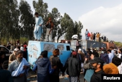 Supporters of former Pakistani Prime Minister Imran Khan climb on shipping containers, placed to block the road, during a clash outside the federal judicial complex in Islamabad, March 18, 2023.