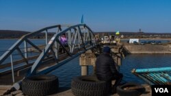 在乌克兰哈尔科夫州，在曾被俄罗斯占领的地区搭建的一座临时桥梁让人们可以越过湖水抵达与俄罗斯接壤地段。(2023年4月10日，美国之音博夏特拍摄)