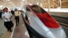 FILE - People walk near a high-speed train during its test at Halim station in Jakarta, Indonesia, Sept. 18, 2023.