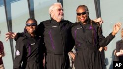 Space tourists, from left, Anastatia Mayers, Jon Goodwin and Keisha Schahaff pose for photos before boarding their Virgin Galactic flight at Spaceport America, near Truth or Consequences, New Mexico, Aug. 10, 2023.