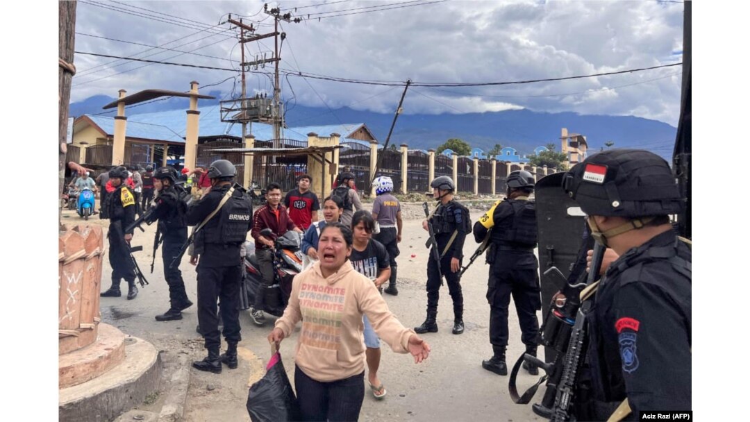 Polisi mengawal warga sipil di Wamena, Papua saat kerusuhan yang dipicu isu penculikan anak, Kamis, 23 Februari 2023. Sepuluh orang tewas dalam kerusuhan itu. (Foto: Aciz Razi/AFP)