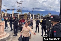 Polisi mengawal warga sipil di Wamena, Papua saat kerusuhan yang dipicu isu penculikan anak, Kamis, 23 Februari 2023. Sepuluh orang tewas dalam kerusuhan itu. (Foto: Aciz Razi/AFP)