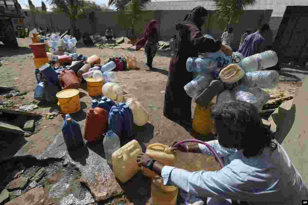 En una barriada de Karachi, Pakistán, varias personas recopilan agua potable en un punto de recolección.