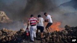 FILE - Local residents try to extinguish a fire, near the seaside resort of Lindos, on the Aegean Sea island of Rhodes, southeastern Greece, on July 24, 2023.