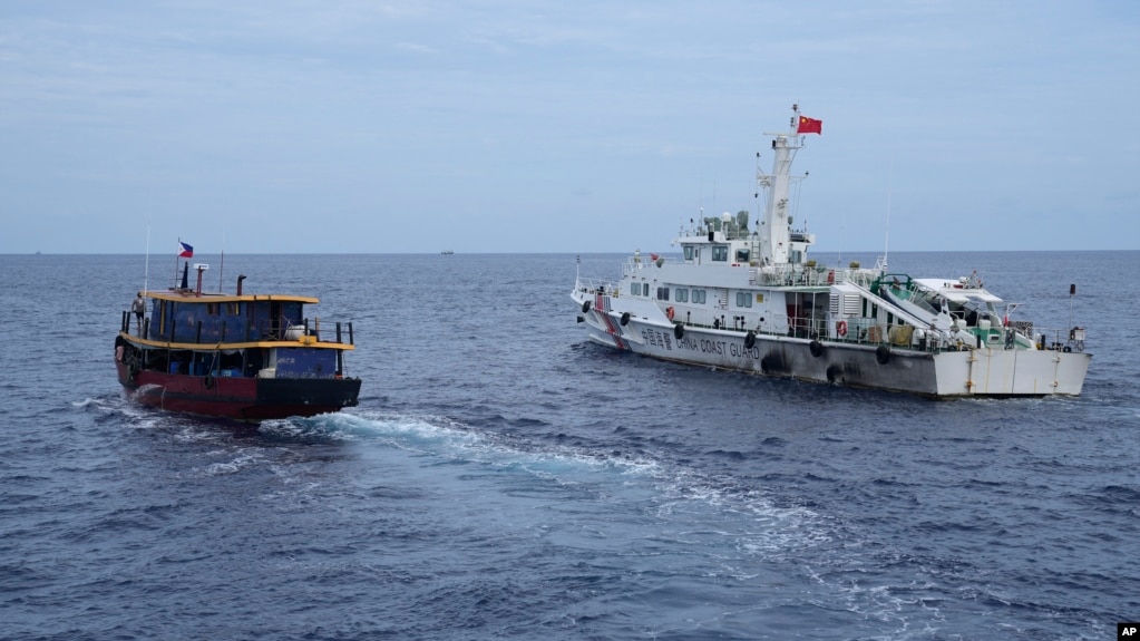 TƯ LIỆU - Một tàu tiếp tế của Philippines (trái) cố gắng tránh một tàu hải cảnh của Trung Quốc ngoài khơi Bãi cạn Second Thomas, ở vùng Biển Đông có tranh chấp trong một nhiệm vụ luân chuyển và tiếp tế, ngày 22 tháng 8 năm 2023. 