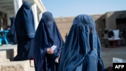 FILE - Afghan burqa-clad women stand in a queue as they wait to receive food being distributed as an aid by the World Food Programme (WFP) organisation at Nawabad Kako Sahib area in Baraki Barak district of Logar Province, Jan. 7, 2024. 