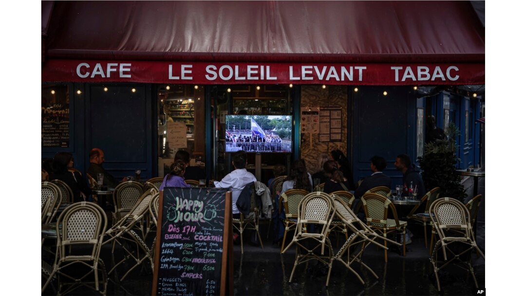 People watch a TV showing the opening ceremony of the 2024 Summer Olympics in a bar in Paris, France, July 26, 2024.