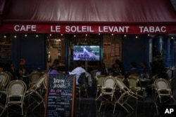 People watch a TV showing the opening ceremony of the 2024 Summer Olympics in a bar in Paris, France, July 26, 2024.