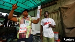 A poll worker holds up a ballot paper during the counting process of Nigeria's presidential election at a polling unit in Awka, Anambra state, Nigeria, Feb. 25, 2023.