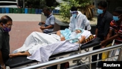 বাংলাদেশের ঢাকায়, উত্তর সিটি কর্পোরেশন কোভিড-১৯ অস্থায়ী হাসপাতালে চিকিৎসার জন্য নিয়ে যাওয়া হচ্ছে করোনাভাইরাসে সংক্রমিত একজন রোগীকে। ১ এপ্রিল, ২০২১। (ফাইল ছবি) 