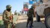 FILE - Ugandan peacekeepers with the African Transition Mission in Somalia (ATMIS) stand next to their armored vehicle on a street in Mogadishu, May 10, 2022.